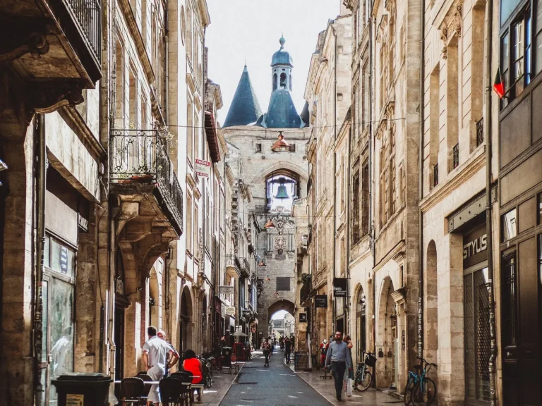 A narrow street in Bordeaux's old town, with limestone buildings and the Grosse Cloche bell tower ahead