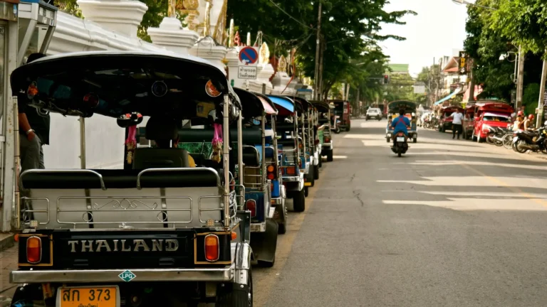 Tuk-tuks lined up along a tree-shaded street in Chiang Mai's old city