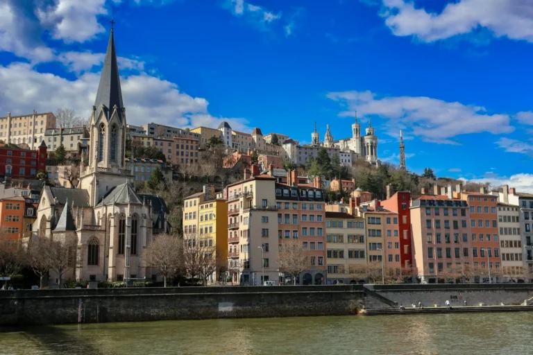 Colourful buildings and a church along the Saône river in Lyon's old town, with the Basilica of Fourvière on the hilltop