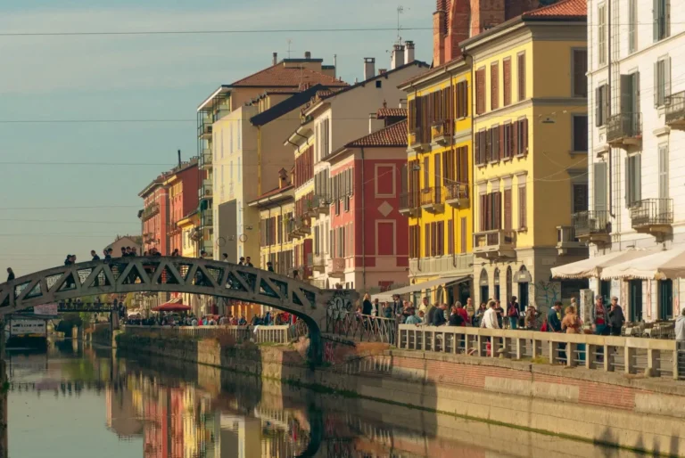 The Navigli canal district in Milan, with colourful buildings and an iron footbridge reflected in the water