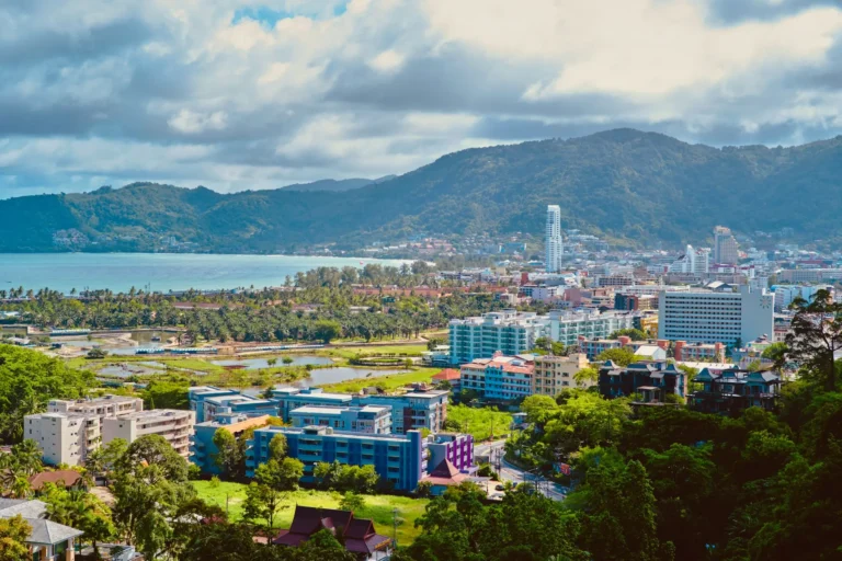 Aerial view of Phuket town and coastline, with green hills, hotels, and the Andaman Sea