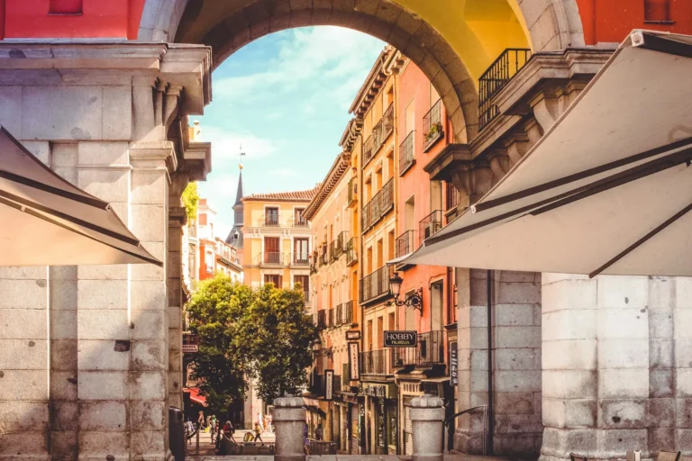 View through historic stone archway into Plaza Mayor in Madrid.